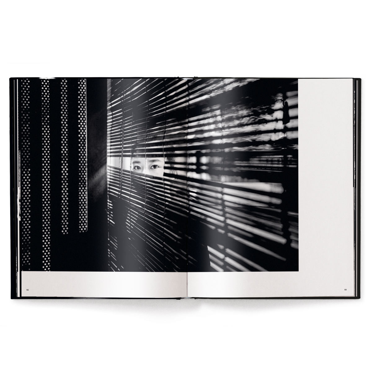 Open book showing a black and white photograph of a textured wall and window blinds.