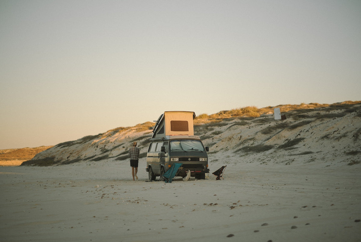 A Westfalia van on a beach in The Getaways by gestalten