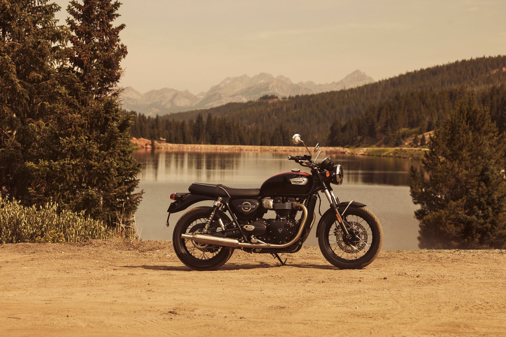 Motorcycle parked by a lake with mountains in the background