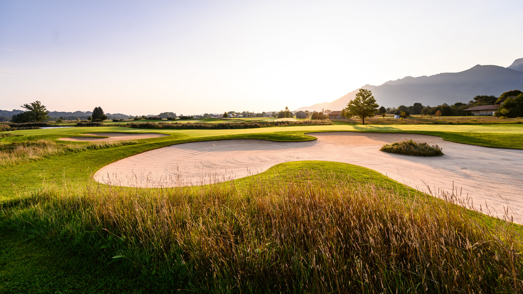 Golf course with a sand bunker and mountains in the background