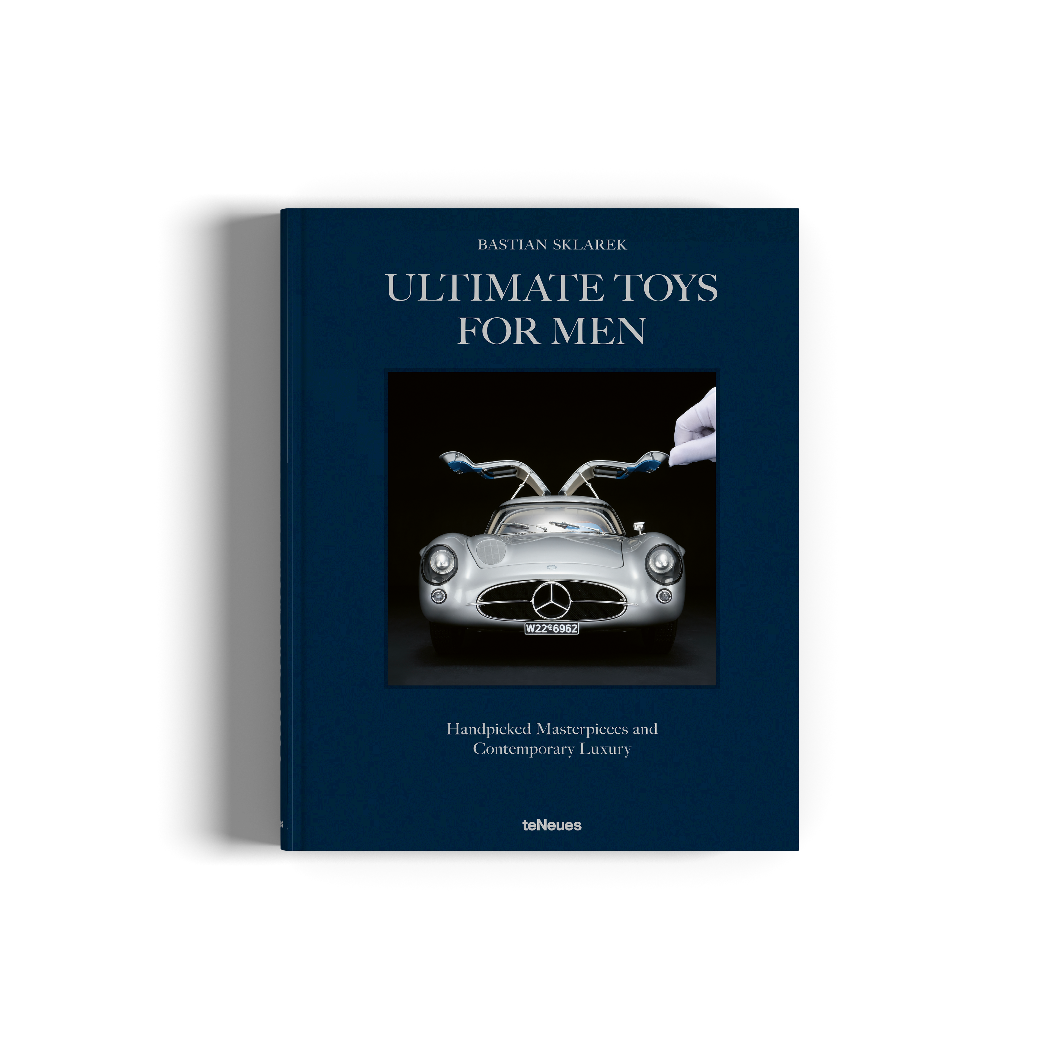 Book titled 'Ultimate Toys for Men' with a Mercedes-Benz car on the cover, on a white background.