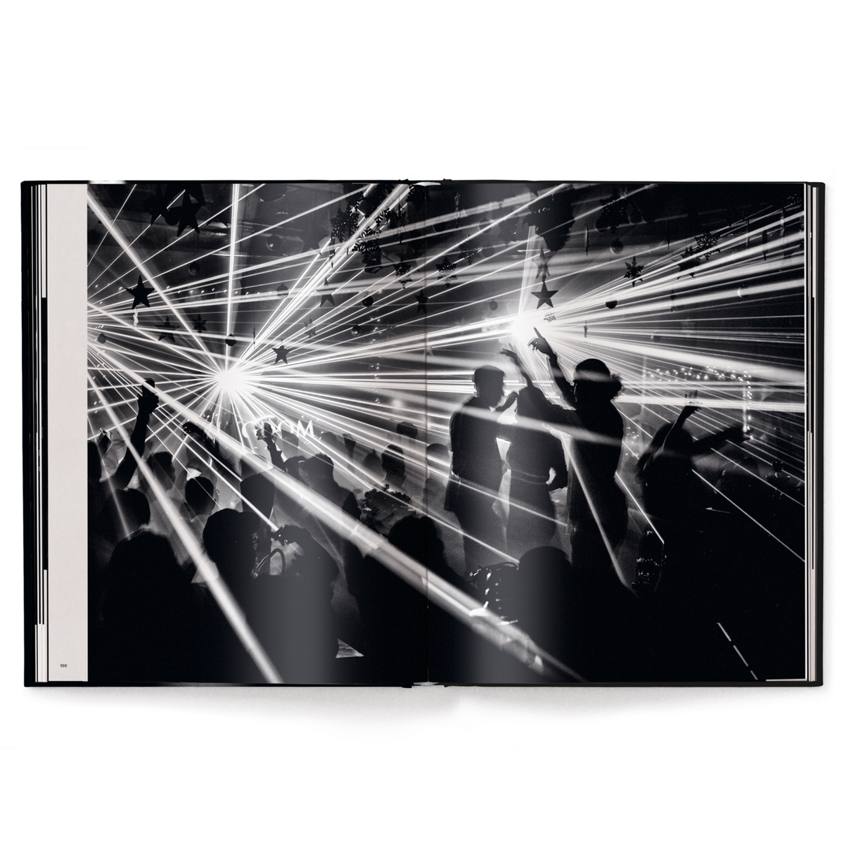 Black and white image of a concert with laser lights and silhouettes of people.