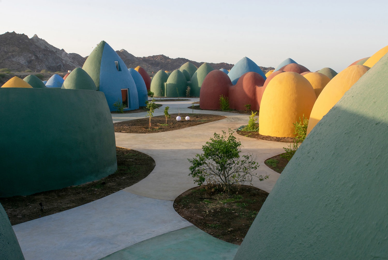 Presence is a tourism complex built on the island of Hormuz, Iran, to stimulate the local economy and offer more autonomy to the community. The island is located on its namesake strait, which is the key passage for Middle Eastern petroleum exportation. It is a site of geological wonder, made up of colorful landscapes including an ochre-red beach and rainbow mountains. The Superadobe Domes of Hormuz by ZAV Architects in Iran are featured in The ArchDaily Guide to Good Architecture.